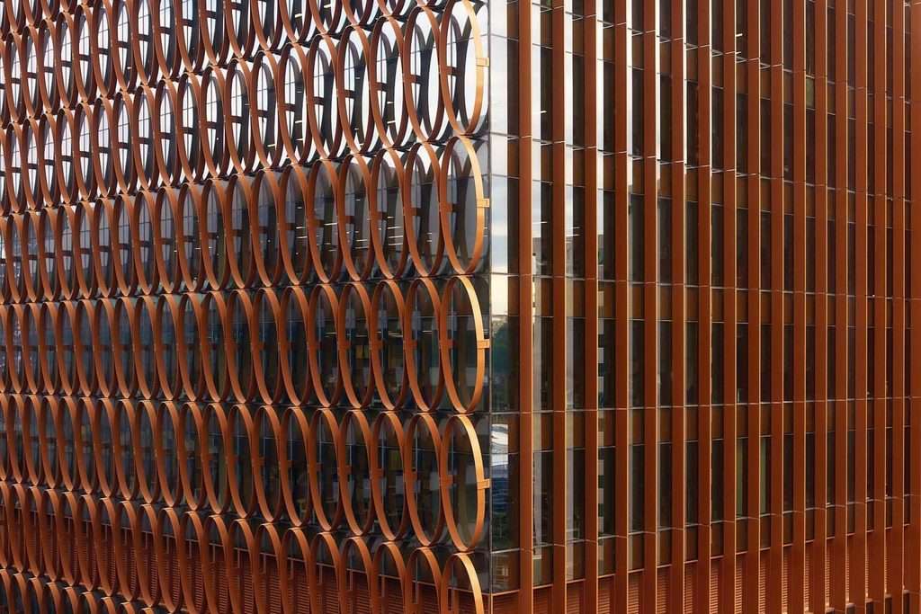 Close-up of copper-anodized aluminum elliptical shades and vertical fins on transparent glazing