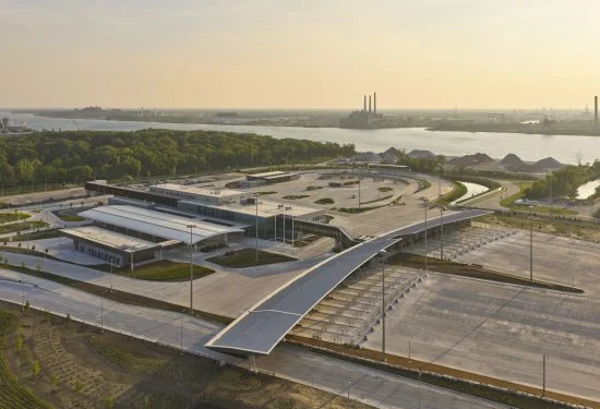 High aerial shot of border terminal buildings, curved canopy structures, and paved circulation areas.