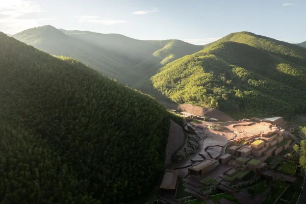 High aerial view of a red architectural complex nestling into dense green forested mountain slopes.