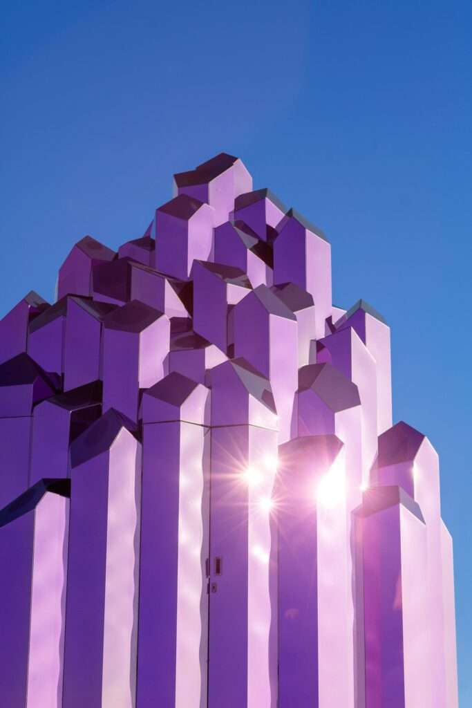Close-up of pink reflective vertical prisms reaching toward a blue sky