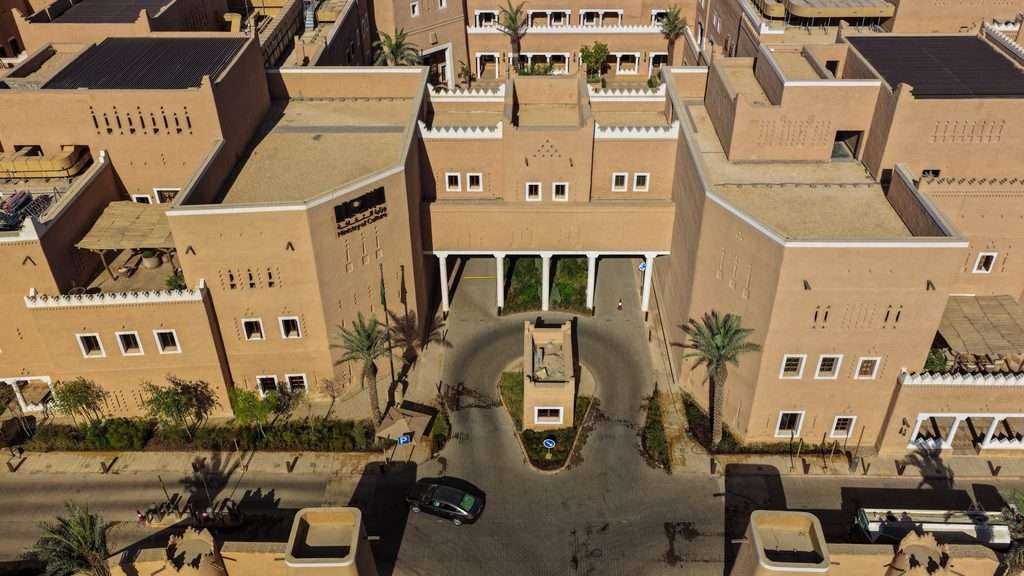 Top-down view of a vehicular drop-off court flanked by earthen building wings.