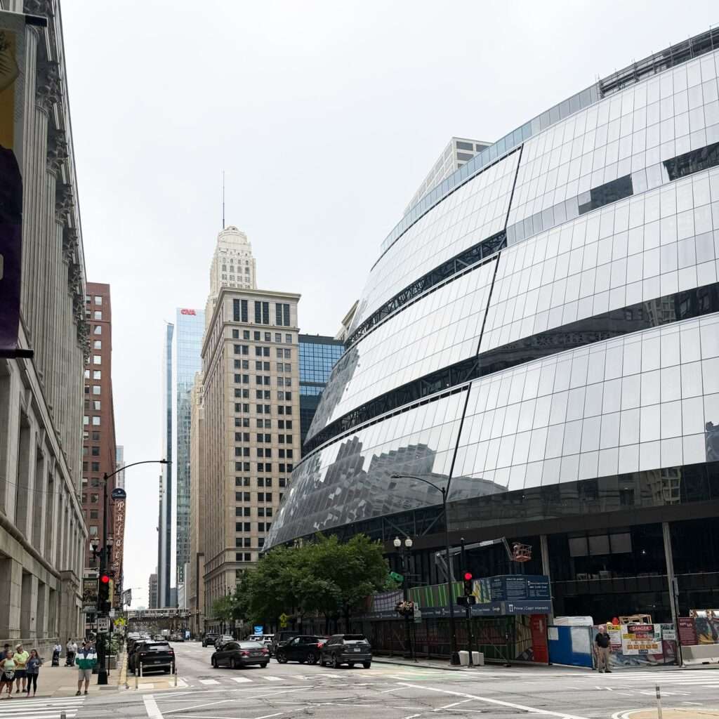 Wide urban street view showing the curved facade of Thompson Center alongside historic masonry buildings.