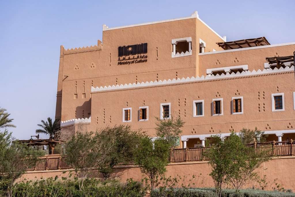 Ground-level view of Najdi textured facade with Ministry of Culture signage and decorative openings.