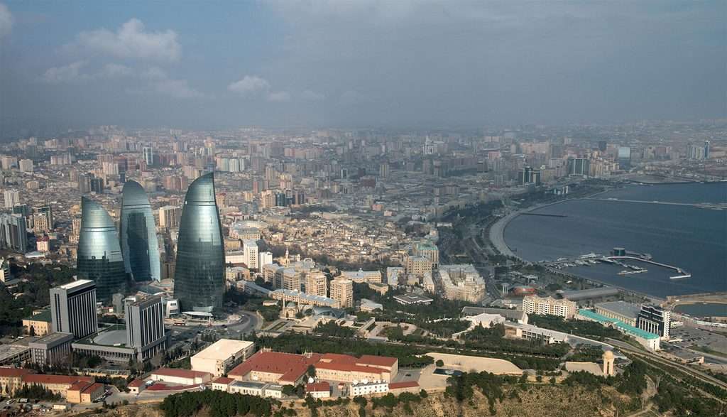 منظر مرتفع لمدينة باكو يظهر أبراج اللهب الثلاثة بالقرب من ساحل بحر قزوين