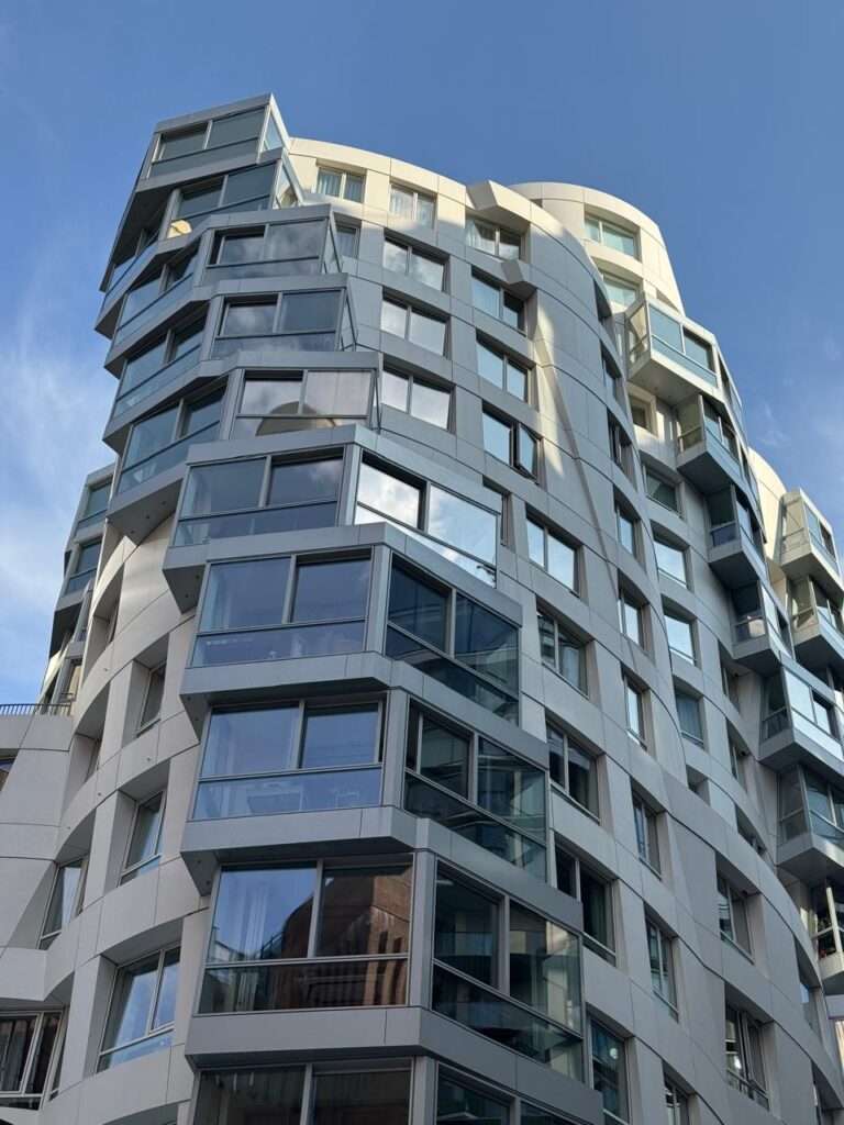 منظر بزاوية منخفضة لمبنى حديث شاهق بجدران منحنية ونوافذ زجاجية بارزة ذات زوايا حادة