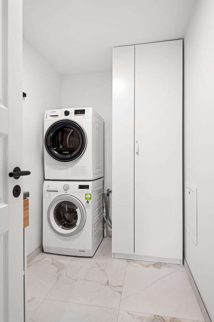 Contemporary laundry room featuring stacked washer and dryer in a minimalist design.