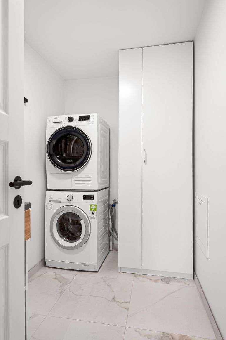 Contemporary laundry room featuring stacked washer and dryer in a minimalist design.