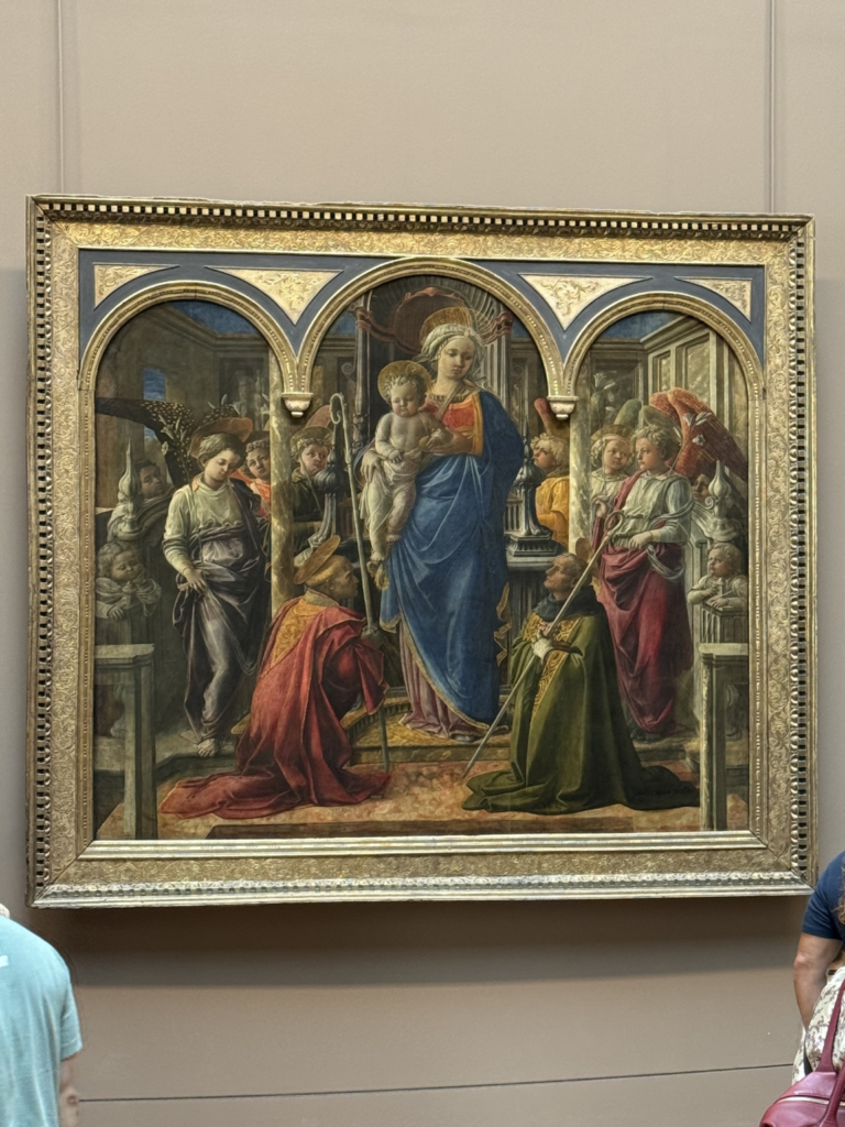 Fra Filippo Lippi's Barbadori Altarpiece depicting the Virgin Mary holding the Christ Child, surrounded by angels and two kneeling saints, set within a gilded three-arched architectural frame.