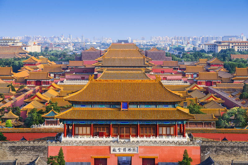 High-angle view of the Gate of Divine Prowess with traditional yellow-tiled roofs and Beijing skyline.