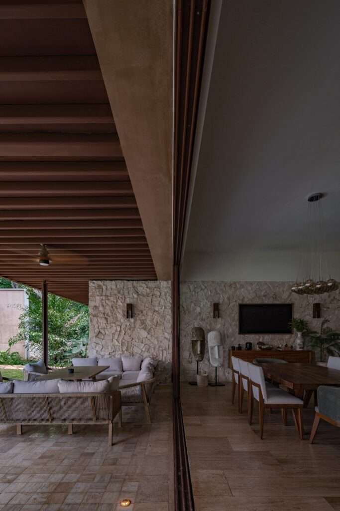 Sliding glass doors dividing outdoor terrace seating from the indoor dining room with regional stone walls.