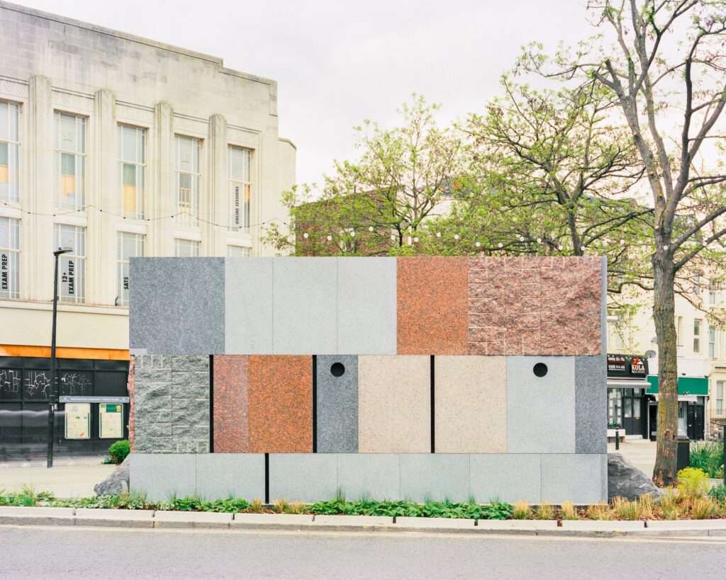Reclaimed granite and larvikite stone facade of Maida Hill public toilet pavilion showing contrasting cut and polished surface textures.