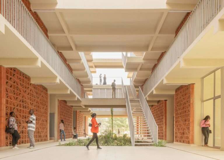 Central open-air atrium corridor featuring terracotta breeze-block walls, multi-level walkways, and students at Cheikh Anta Diop University student housing.