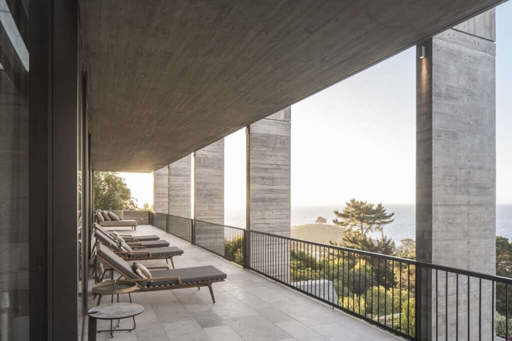 Long board-formed concrete balcony with sun loungers overlooking the ocean at Casa Zapallar.