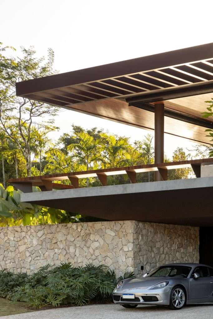 Close-up of the cantilevered upper terrace of Casa da Mata featuring custom timber benches, a dark steel column, and a textured fieldstone wall below.