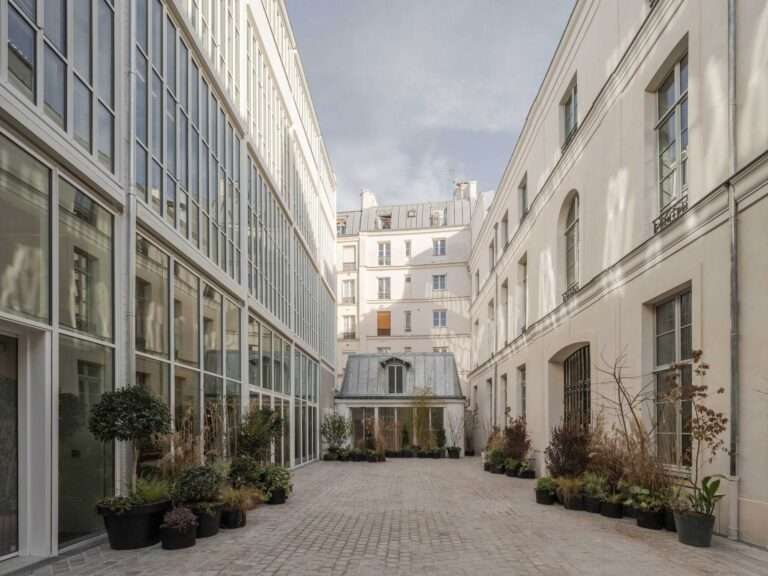 Paved inner courtyard of Rue Pavée project showing contrast between restored classical stone facade and modern glazed industrial facade.