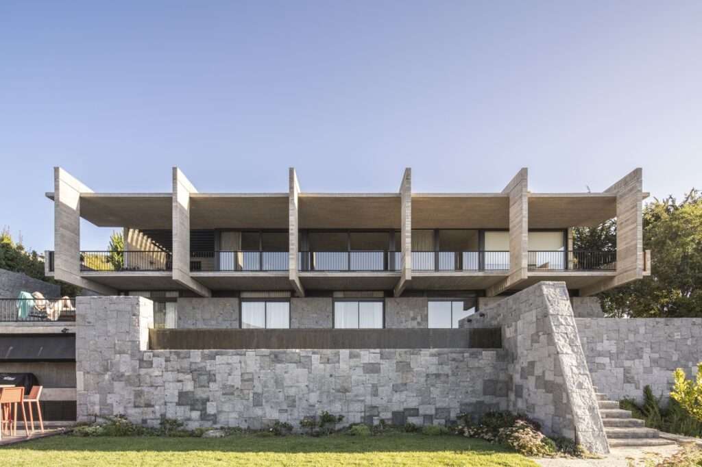 Front elevation of Casa Zapallar featuring a stereotomic stone masonry base supporting a cantilevered concrete upper level.
