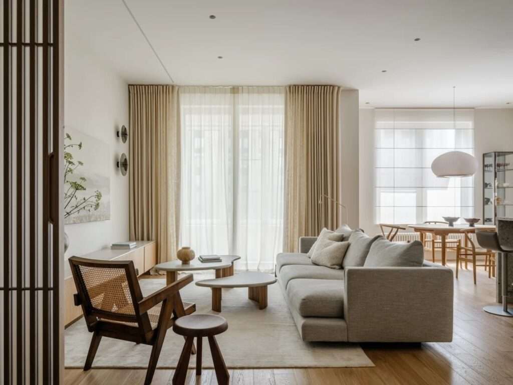 Modern open-plan living room in Residence Open featuring custom wooden furniture, soft beige curtains, and organic coffee tables.