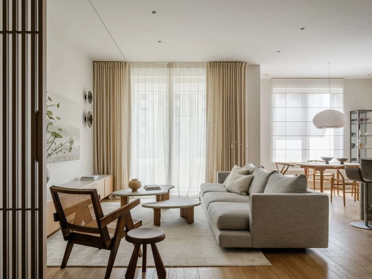 Modern open-plan living room in Residence Open featuring custom wooden furniture, soft beige curtains, and organic coffee tables.