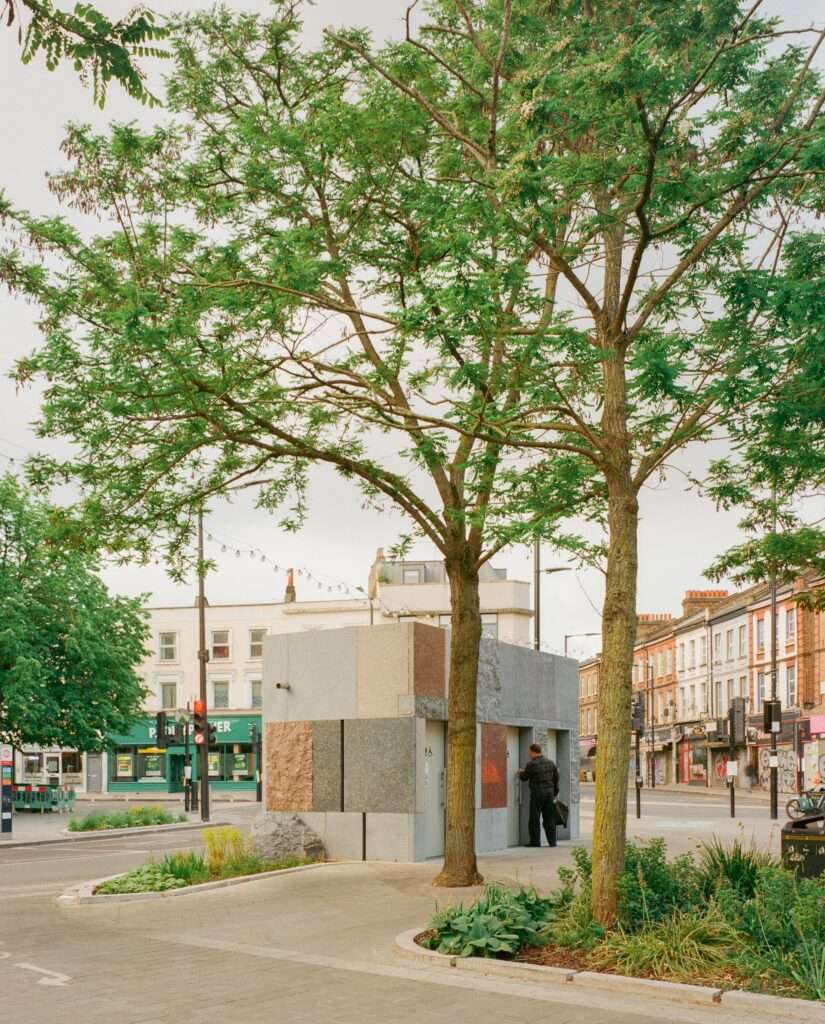 Pedestrian entering the Maida Hill public toilet pavilion surrounded by mature trees and streetscape planter beds.