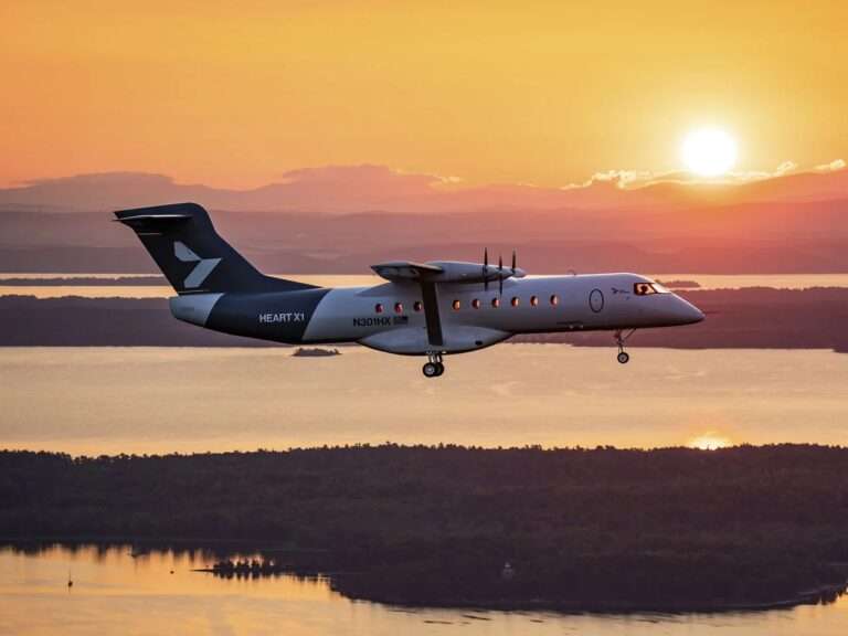 Side profile of the Heart X1 experimental electric aircraft cruising in flight against a golden sunset over a scenic landscape.