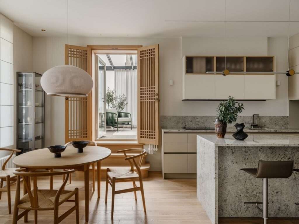 Dining area featuring a round wooden table and Hans Wegner Wishbone chairs adjacent to custom Korean-inspired oak screen doors.
