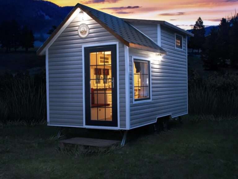 Exterior view of the Sunrise Tiny House built on a 20-foot double-axle trailer with Finnish pine cladding at dusk.