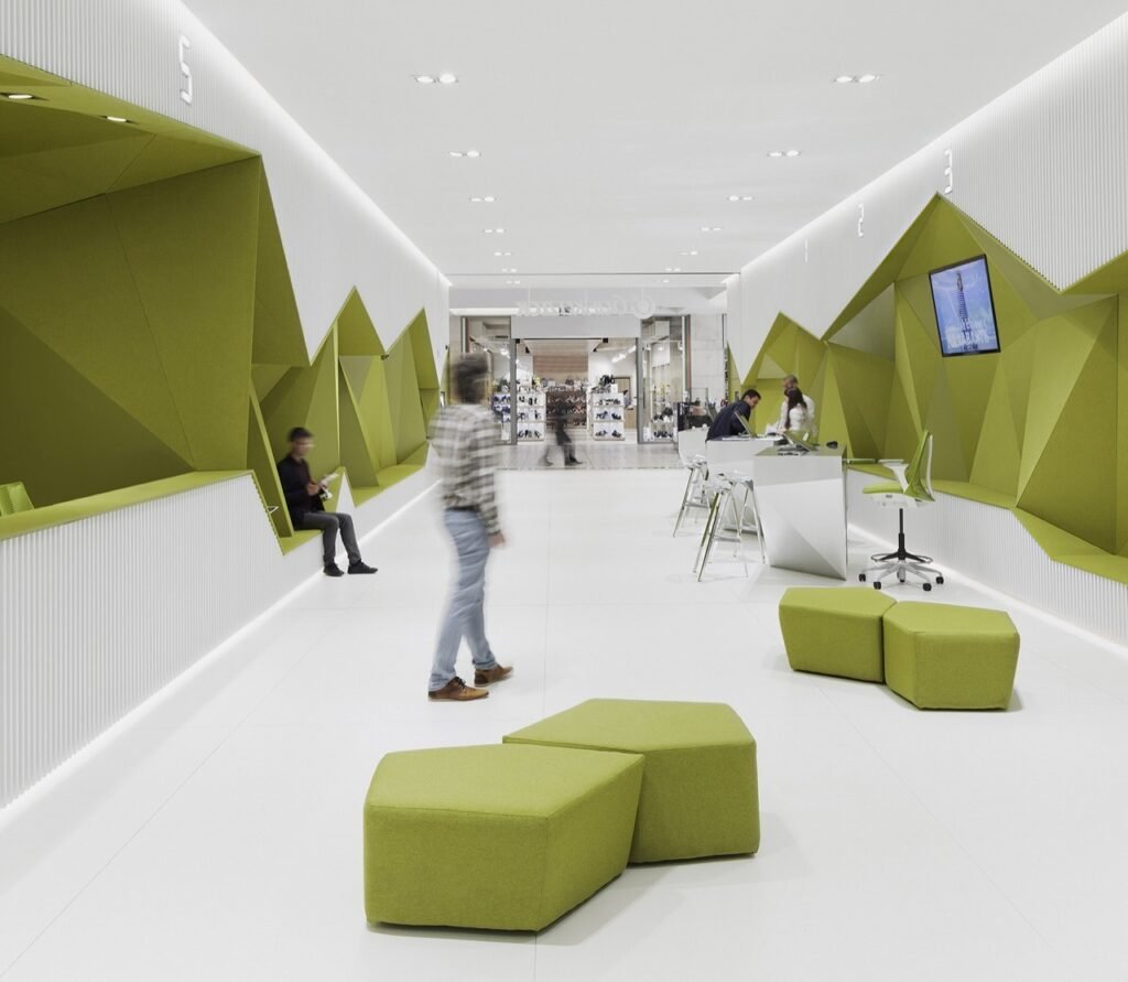 Wide perspective of DSK Bank interior in Sofia, showing an open central space with service points pushed to the perimeter, defined by the geometric olive-green and white ribbon.