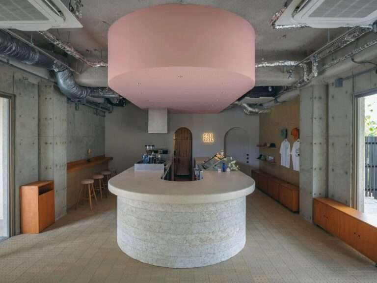 Semicircular counter made of local lime plaster and concrete with a suspended soft pink curved ceiling volume inside SR Ice Cream shop in Miyakojima.