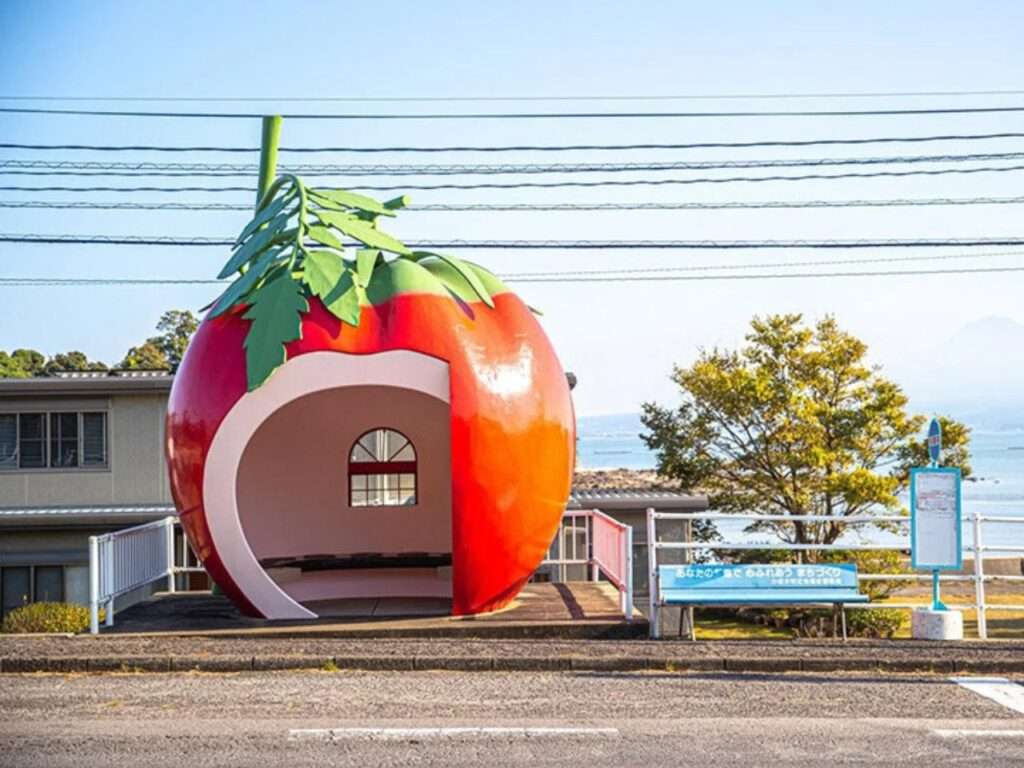 Front view of a tomato-shaped bus stop shelter with a hollowed entryway and leaf details on Route 207 in Konagai.
