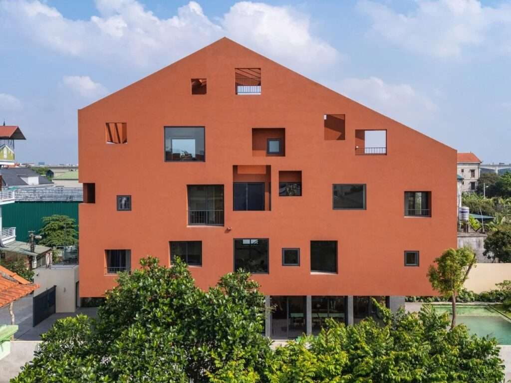 Front elevation of 100 Windows House featuring a terracotta double-skin façade with randomized geometric openings.