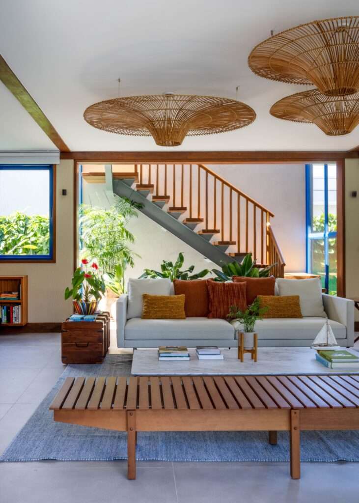 Contemporary living room setup with white sofa, terracotta cushions, slatted wood bench, and a steel and timber staircase leading to the upper floor.