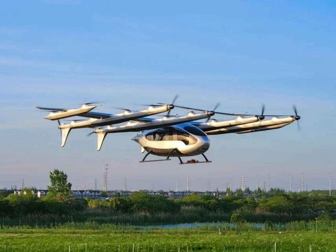 AutoFlight Prosperity eVTOL aircraft with multiple rotors flying over a green field.