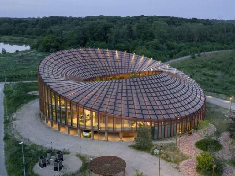 Aerial view of the circular Dymak HQ designed by BIG showing its undulating Möbius strip roof integrated with customized photovoltaic solar panels in Odense.