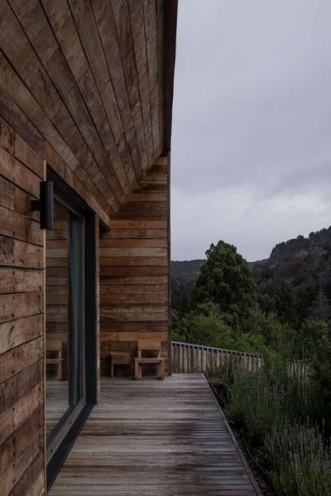 Covered outdoor deck with natural weathered Guaica timber wall cladding and large glass sliding door at Casa El Trébol.