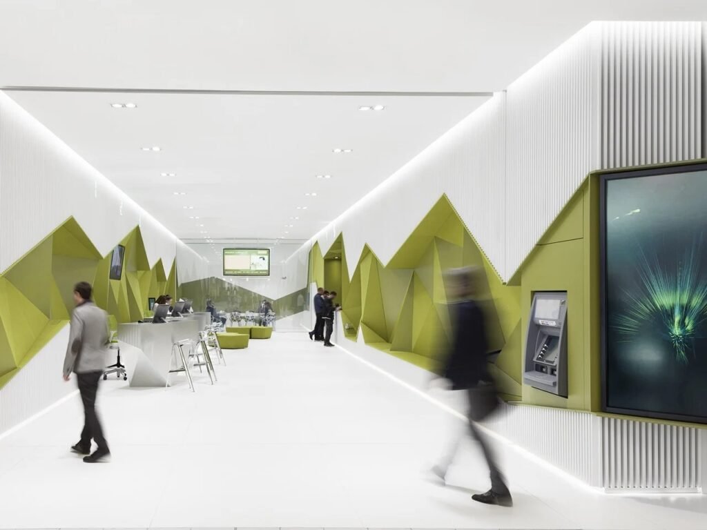 Detailed view of the DSK Bank perimeter wall integrating service points, a digital screen, and an ATM within the geometric green and white structure, with motion-blurred visitors.