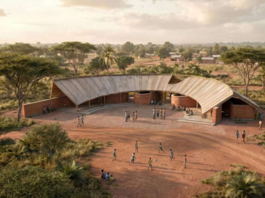 Aerial view of a curved community center in Senegal featuring rammed earth walls and a sloped bamboo roof surrounding an open courtyard gathering space.