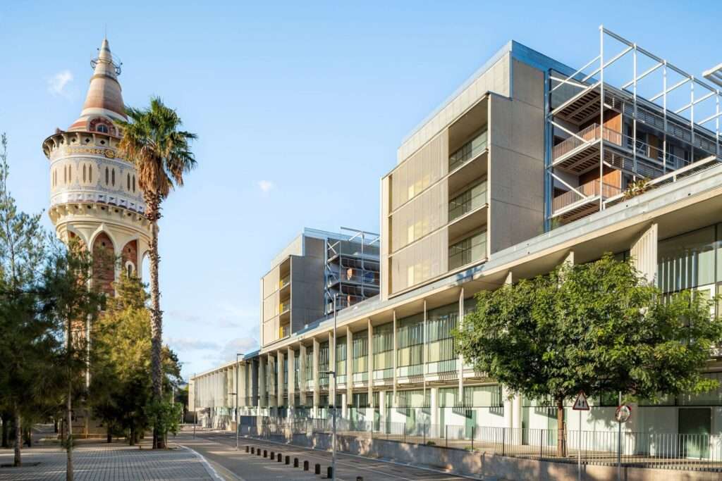 Exterior street-level view of Hospital del Mar expansion alongside the historic water tower in Barcelona.