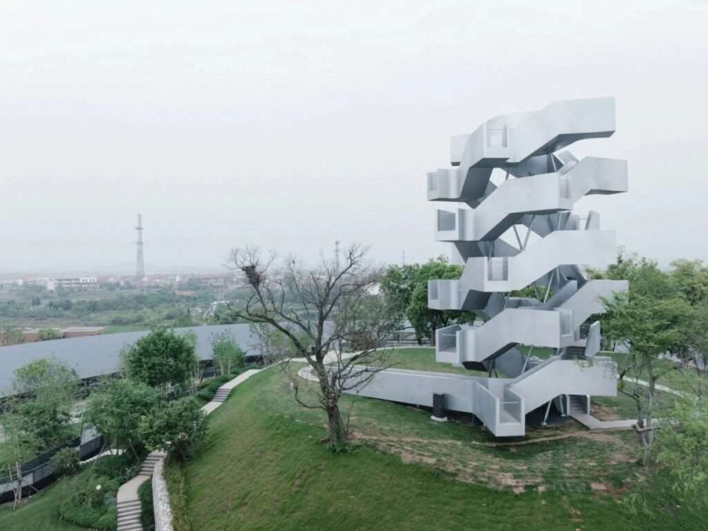 Wide aerial perspective of Qinghu Migratory Bird Observation Tower on Xiangluoshan hill surrounded by trees and landscape paths.