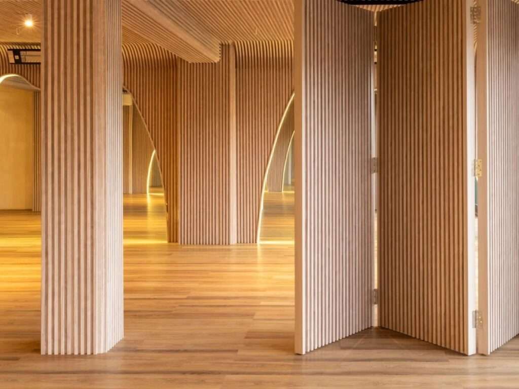 Operable slatted wood folding partitions partially opened between practice areas in Align Studio.