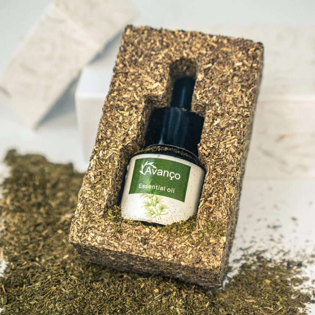 Perspective shot of the textured compressed biomass packaging frame holding the Avanço essential oil bottle against a neutral white background.