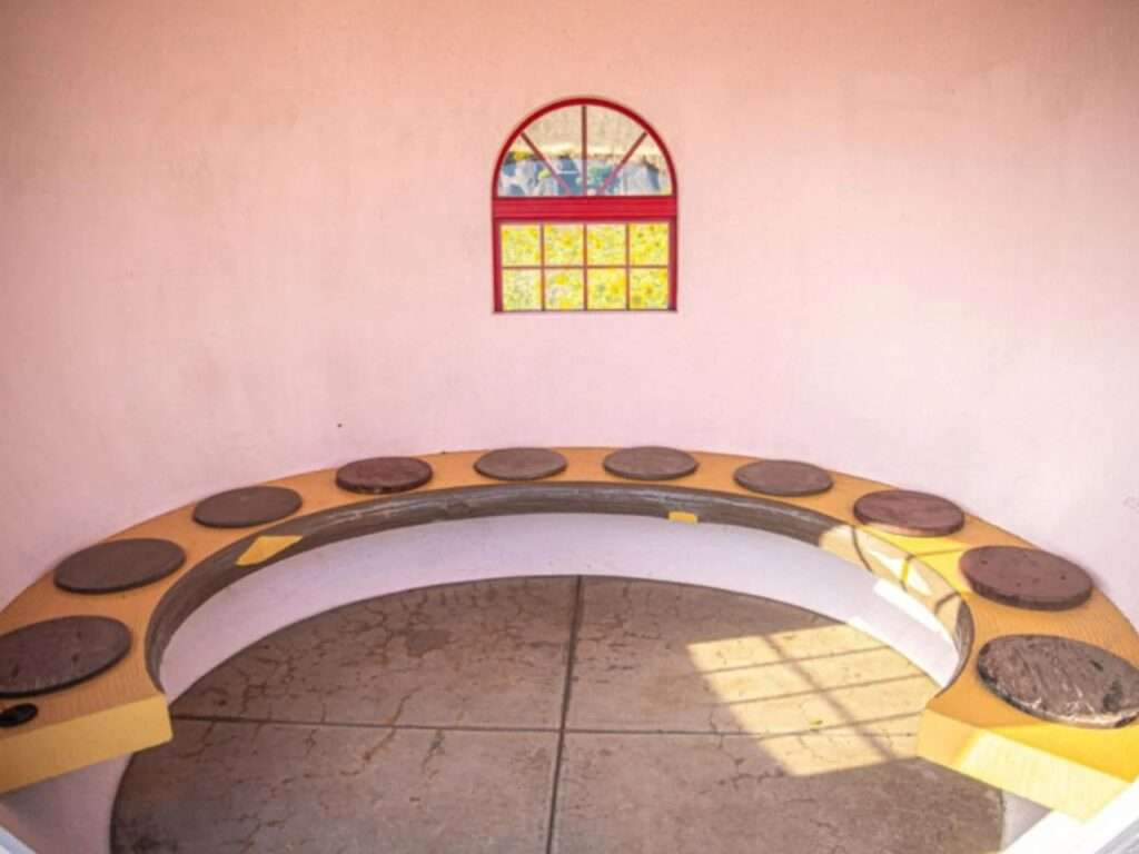 Interior view of a fruit-shaped bus shelter showing a curved bench and a small arched window.