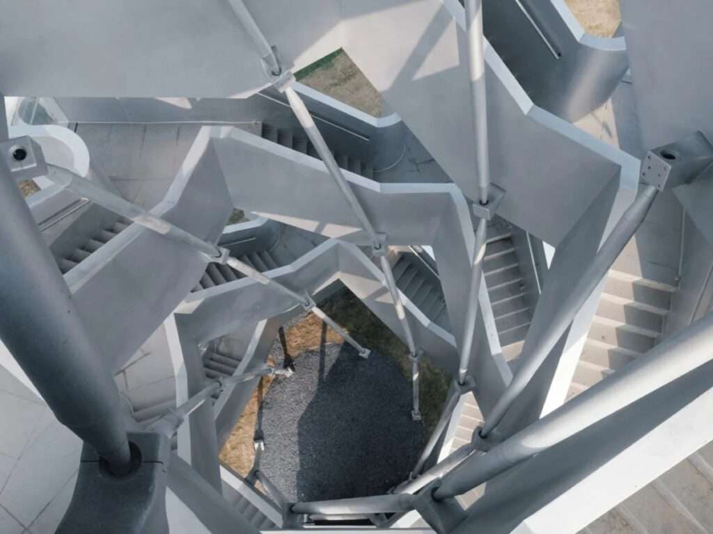 Bird's-eye downward view through the interior central void of Qinghu observation tower showing interlaced stairs and steel struts.