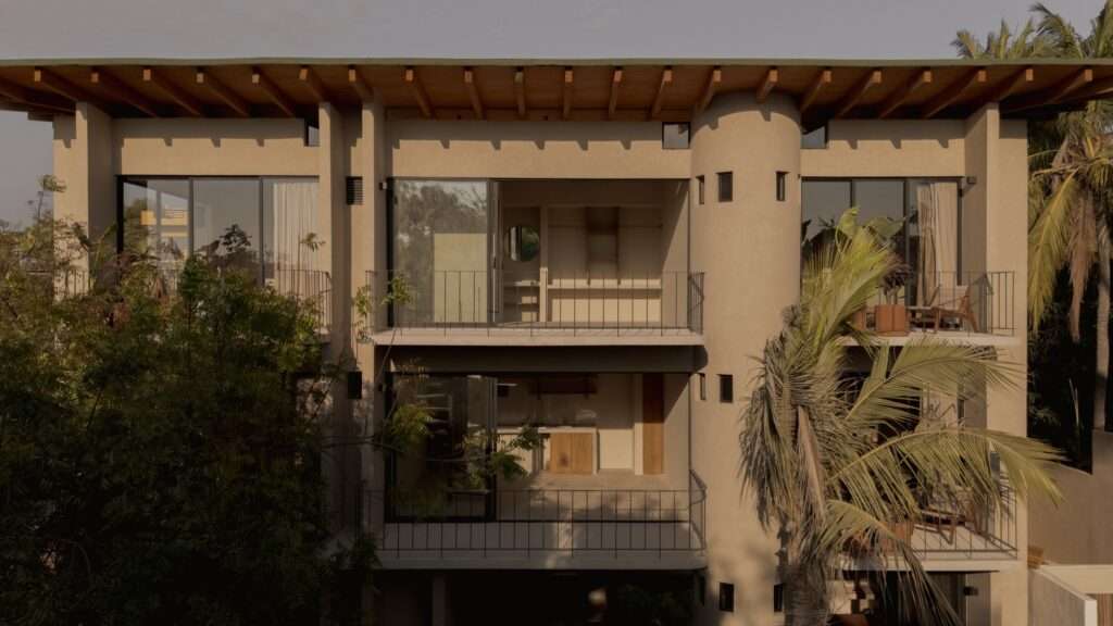 Medium shot of Suuel Living balconies featuring cylindrical concrete circulation cores, timber roof beams, and floor-to-ceiling glass doors.