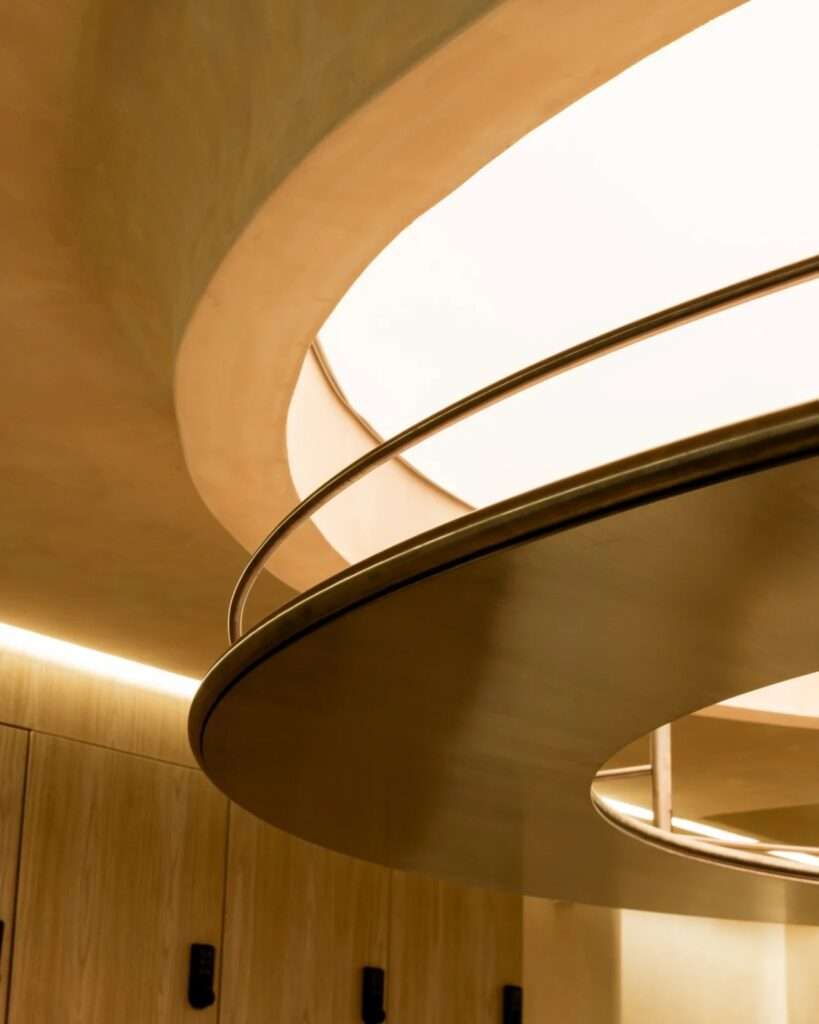 Close-up of a circular ceiling light feature surrounded by smooth beige plaster and metallic detailing.