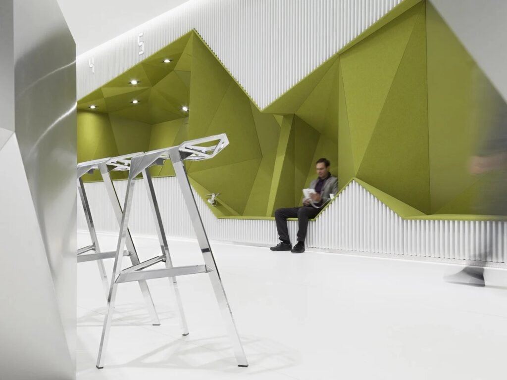 Dynamic view looking across polished stainless steel stools toward the faceted olive-green wall with integrated seating and waiting customers in the DSK Bank in Sofia.