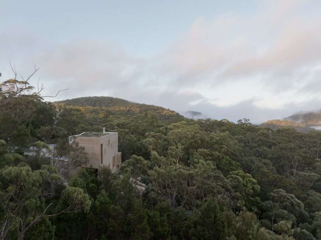 EA House’s multi-level brick structure viewed from an elevated perspective as it descends the slope, surrounded by mature eucalyptus trees.