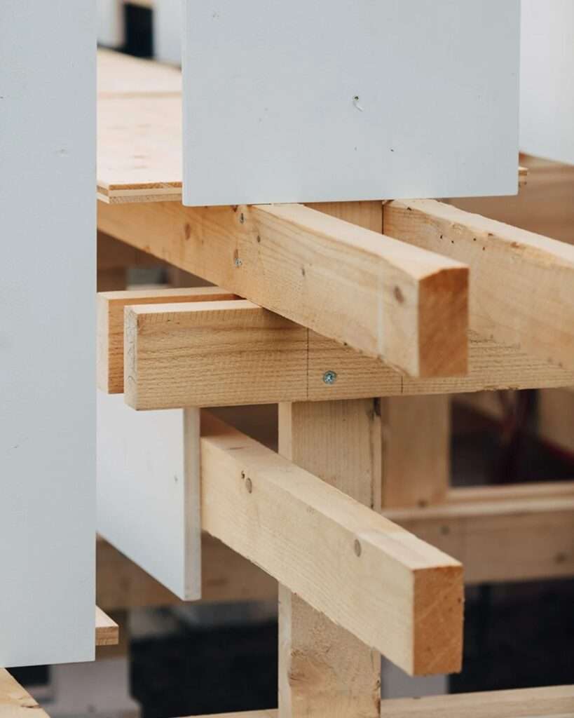 Close-up detail of the wooden construction of the Gabonsa Pavilion, showing precise mechanical screw joins of timber beams and the edges of white panels.