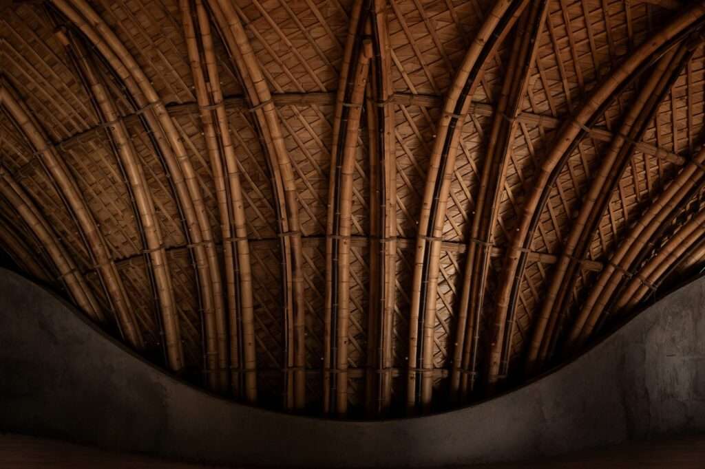 Detailed view of a curved bamboo wall structure seamlessly curving into a woven bamboo ceiling inside Lotus Shala.