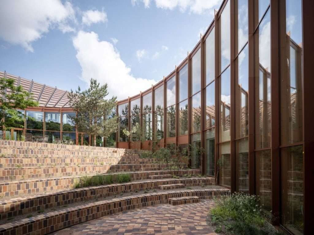 Landscaped central inner courtyard of Dymak HQ with multi-tiered brick-paved amphitheater seating and native planting.