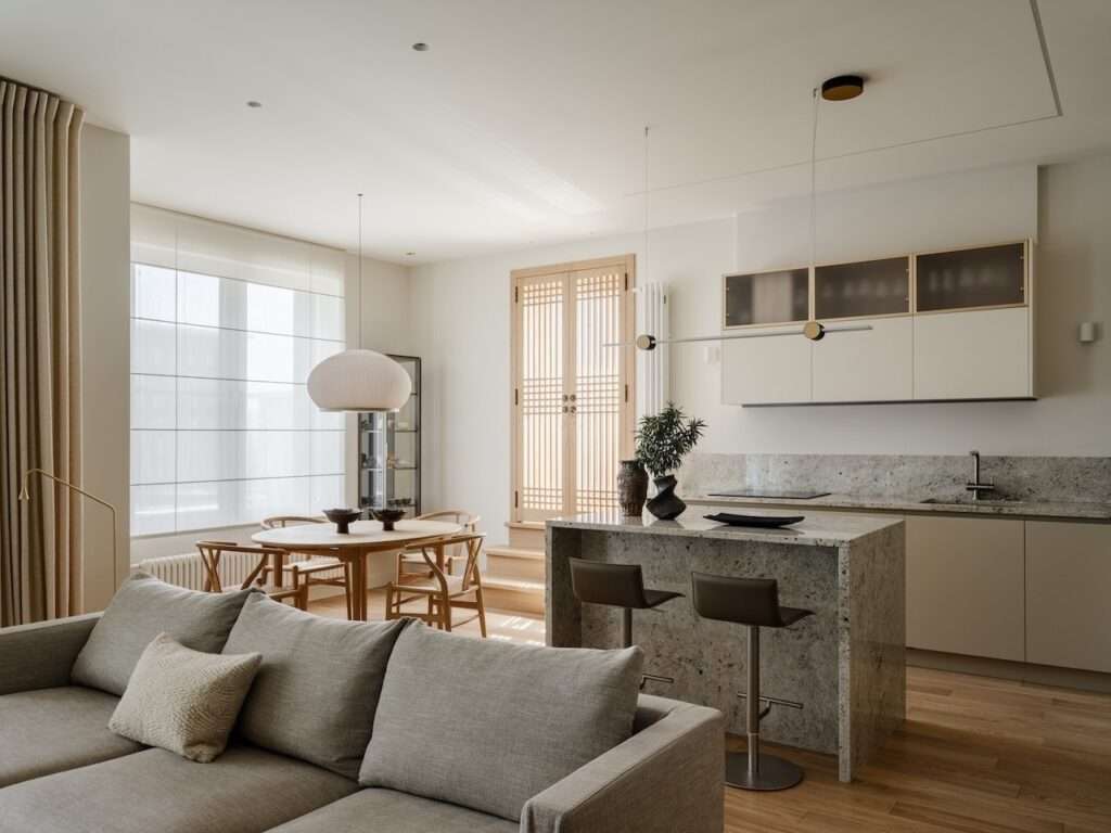 Wide view of the open-concept kitchen, dining, and living area with oak partition doors in the background.